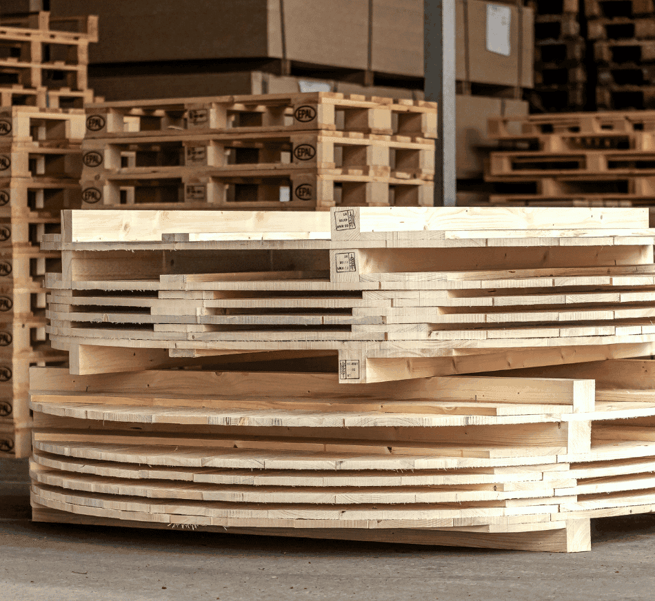 Stacks of wooden round pallets in warehouse environment.