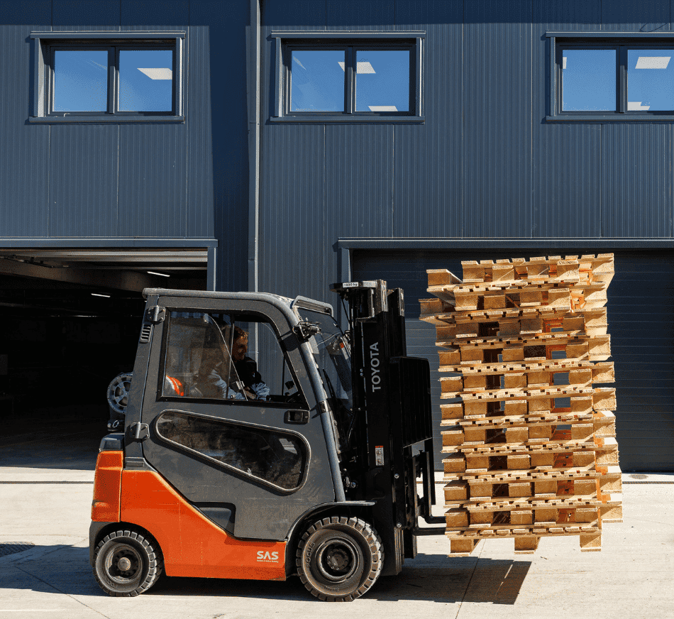 Heavy-duty forklift handling stacked wooden pallets