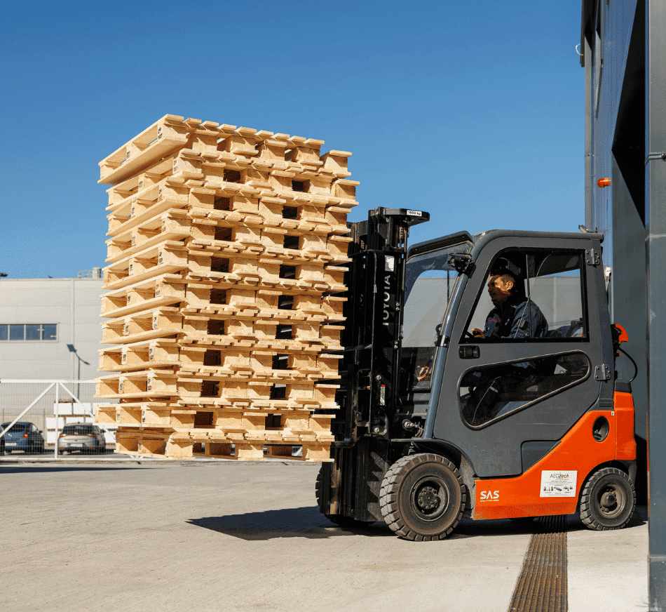 Forklift lifting wooden pallets at warehouse yard.