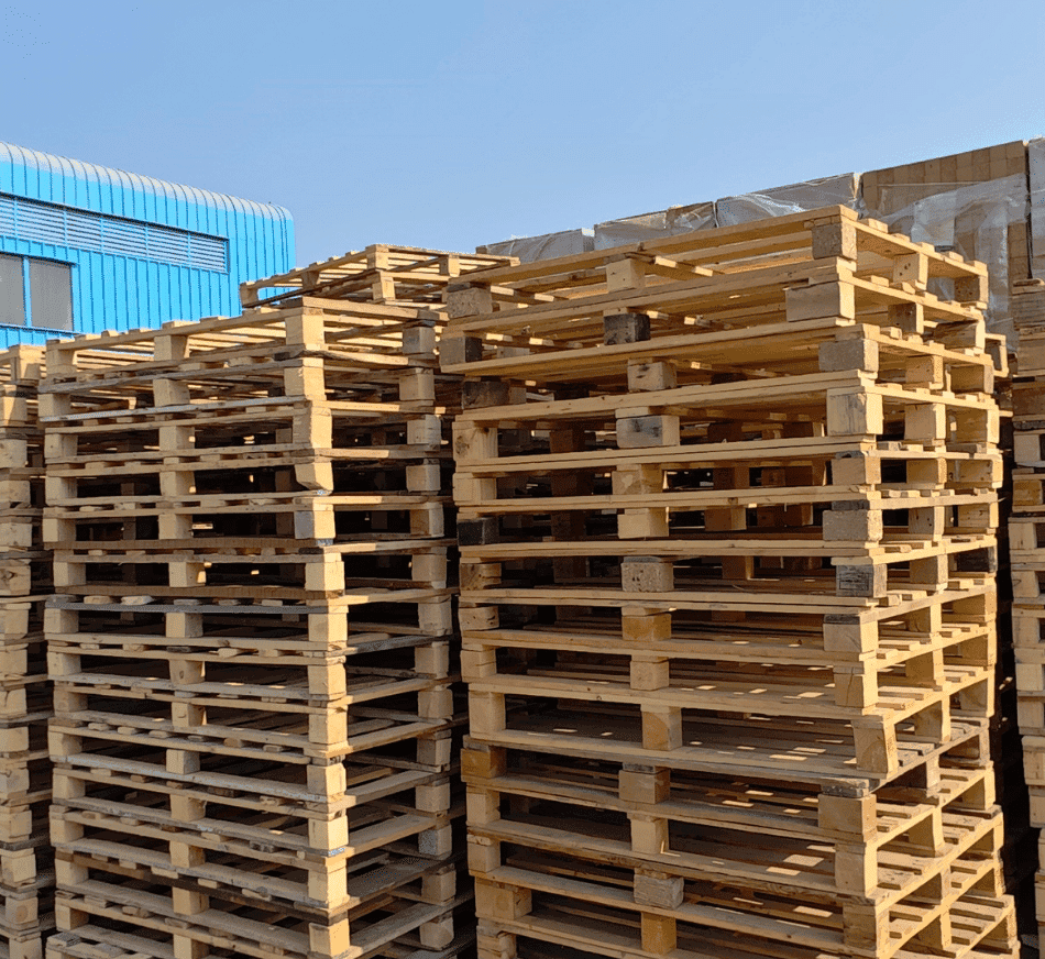 Stacked wooden pallets in an outdoor storage yard, ready for distribution and logistics solutions.