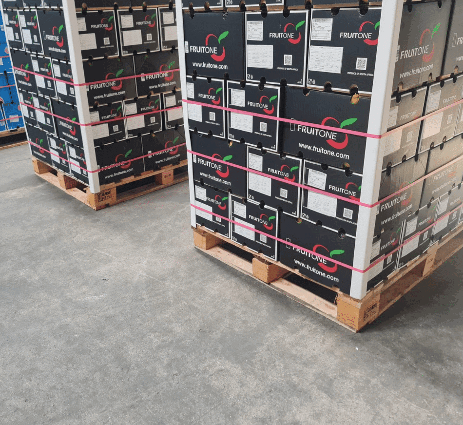 Stacked fruit boxes on pallets at warehouse facility.