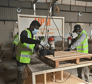 Pallet manufacturing workers assembling wooden pallets in a factory environment.