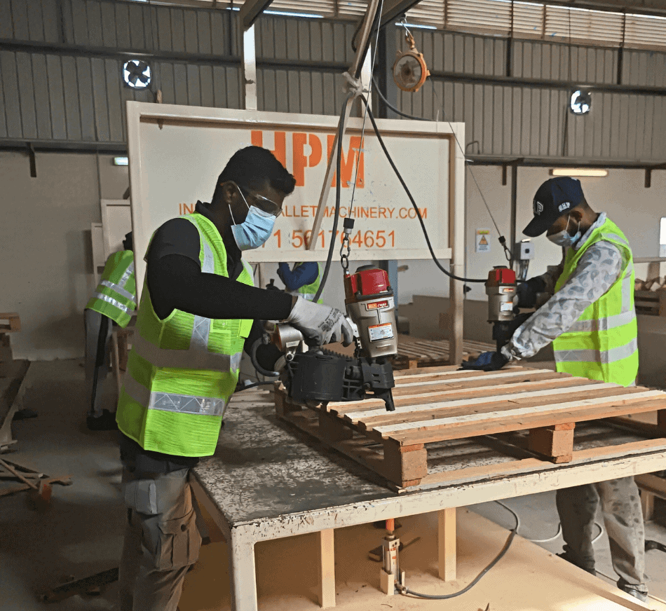 Pallet manufacturing workers assembling wooden pallets in a factory environment.