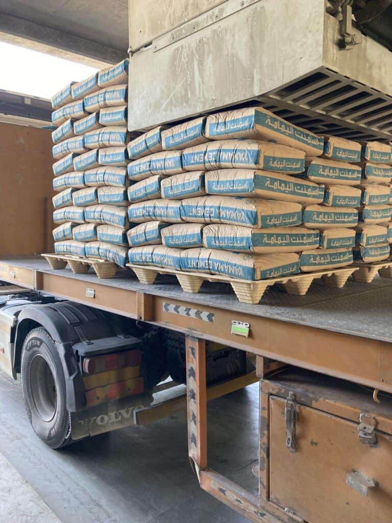 A truck with a load of cement bags on compressed pallets on it