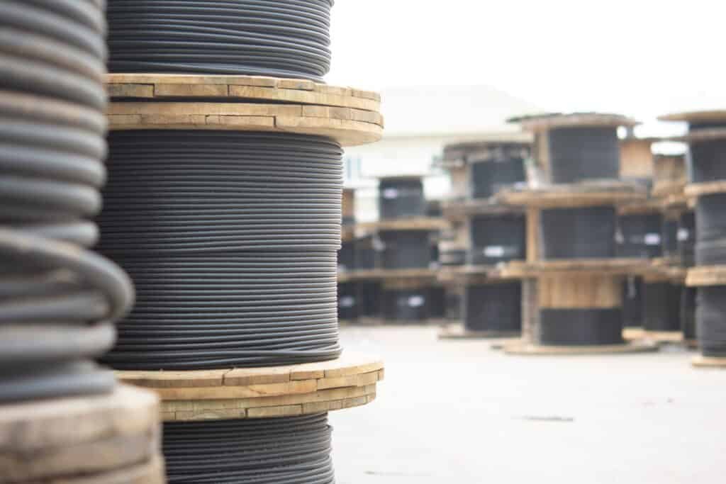 A large pile of wooden cable drums with black wires.
