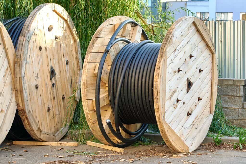 Several large wooden drums with black wires.