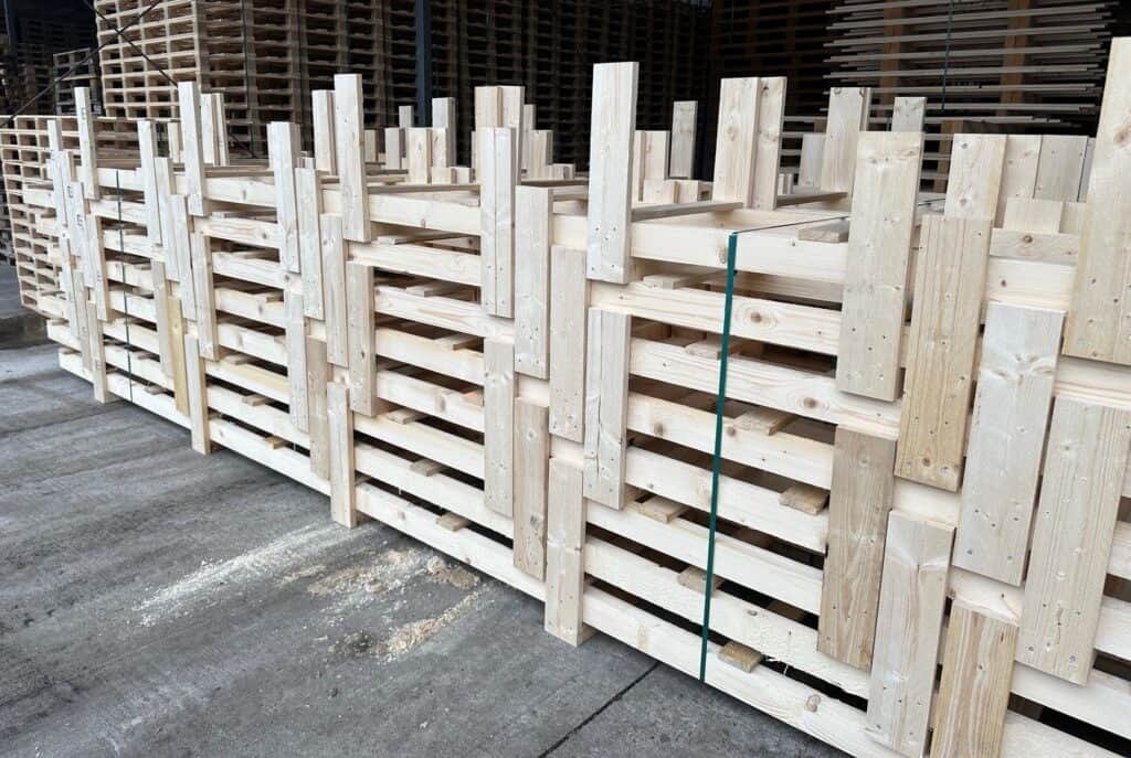 A large pile of wooden pallets in a warehouse.